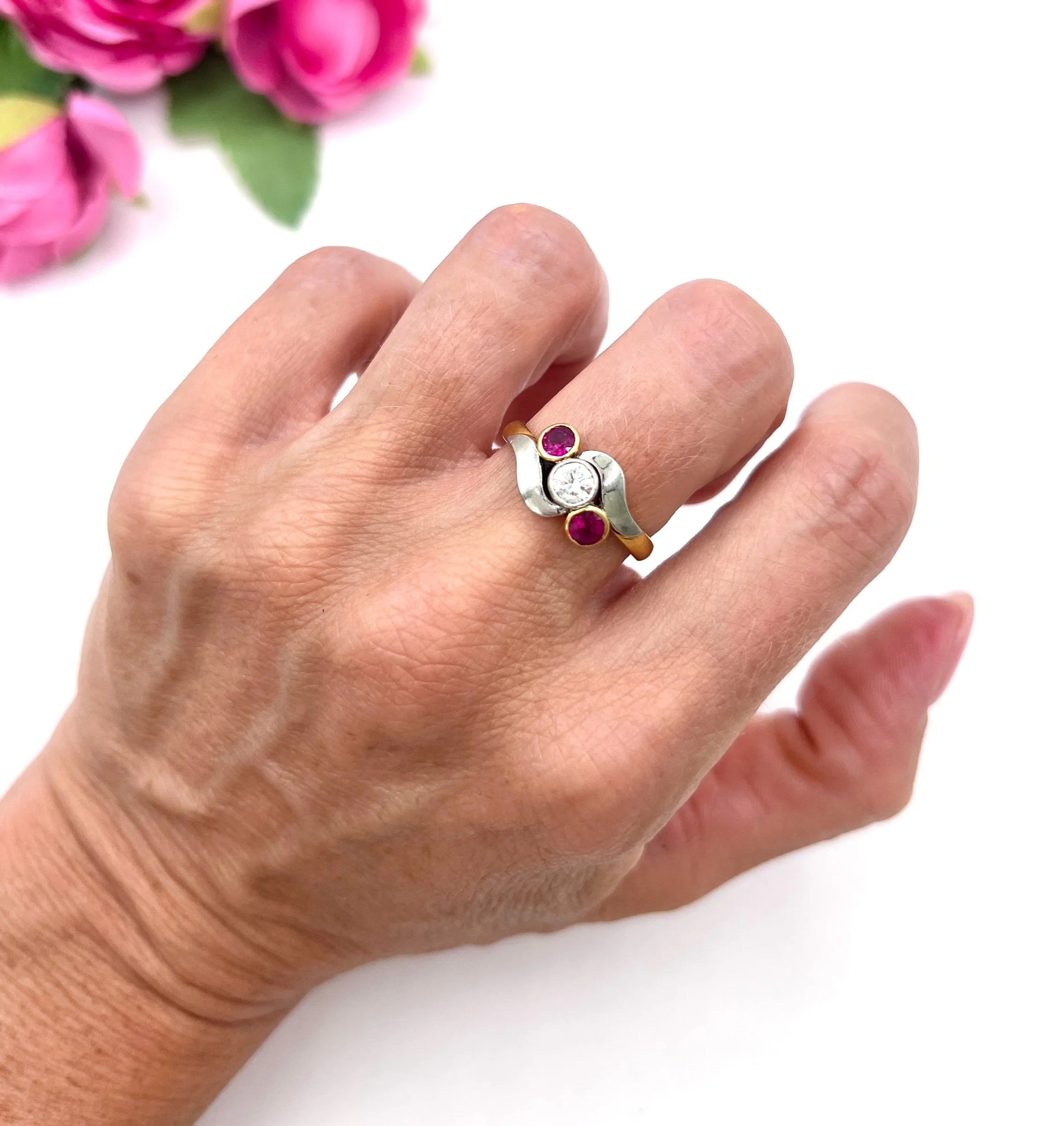 A three stone ruby and diamond crossover ring in platinum and yellow gold, modelled on a hand