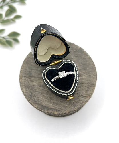 A princess cut diamond solitaire ring in platinum, in a heart-shaped ring box