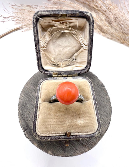 A round orange coral and diamond dress ring in platinum, in an antique ring box
