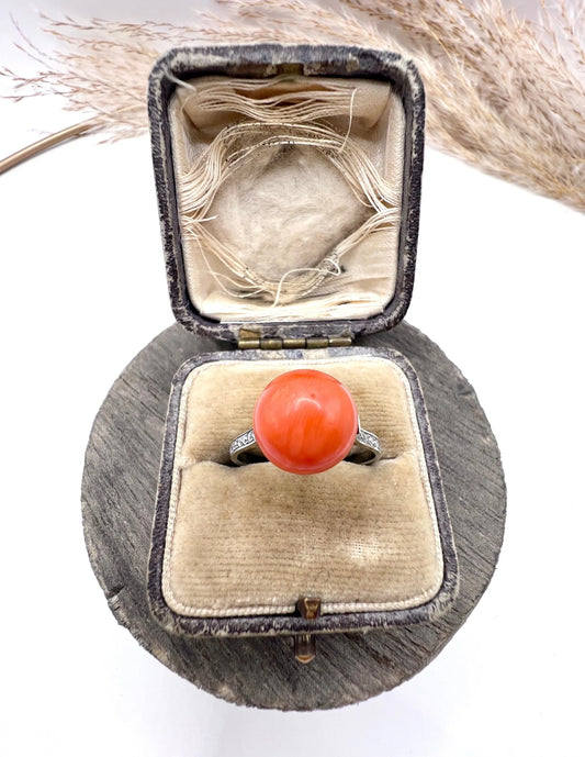 A round orange coral and diamond dress ring in platinum, in an antique ring box