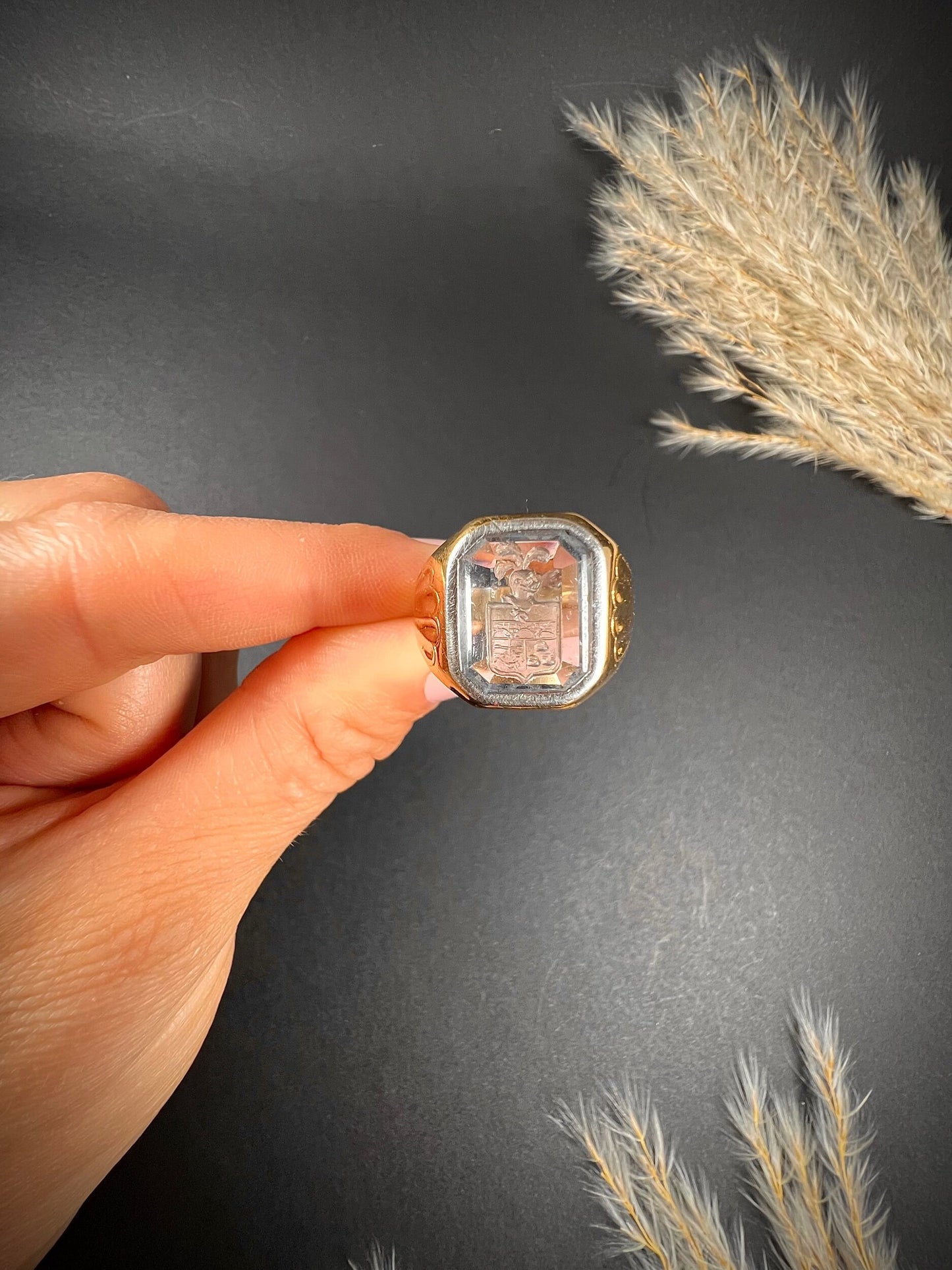 A yellow gold blue glass intaglio signet ring, held in a hand