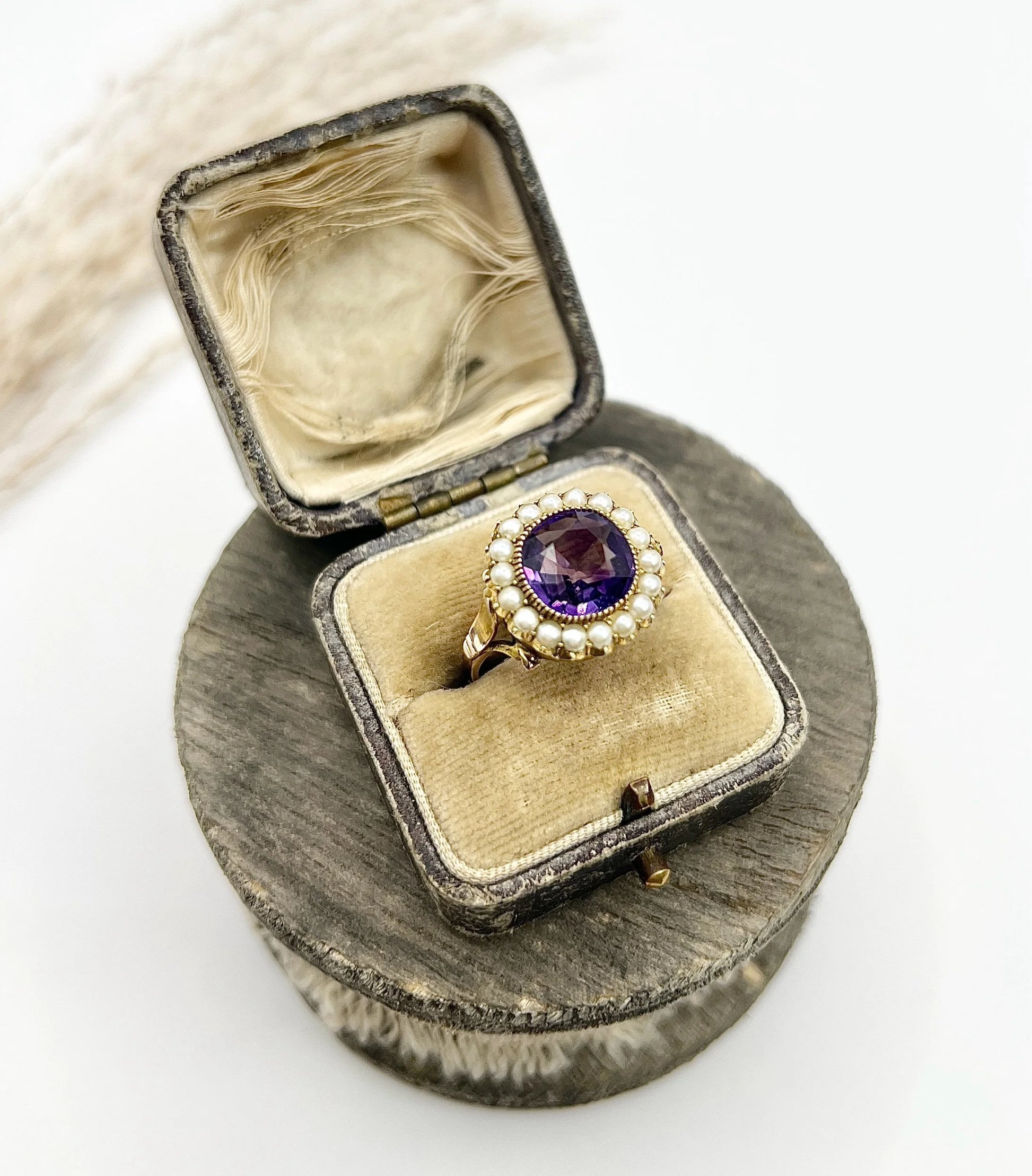 A cushion shaped amethyst cluster ring with a pearl border, in yellow gold, in a box