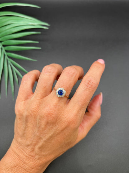 A circular cluster ring with sapphire and diamonds in yellow gold and platinum, modelled on a hand
