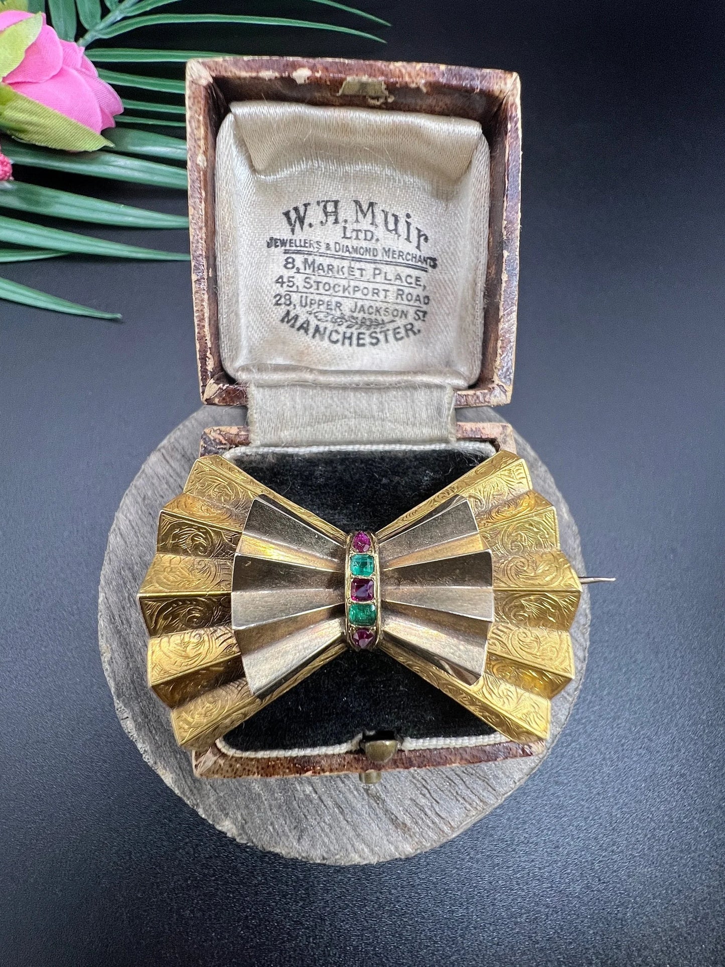 A yellow gold bow shaped brooch with rubies and emeralds