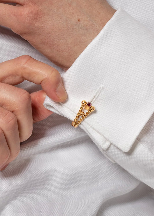 A gold ruby cufflink modelled in a white shirt cuff