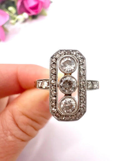 A diamond open cluster ring with three principal diamonds, in yellow and white gold, held in a hand