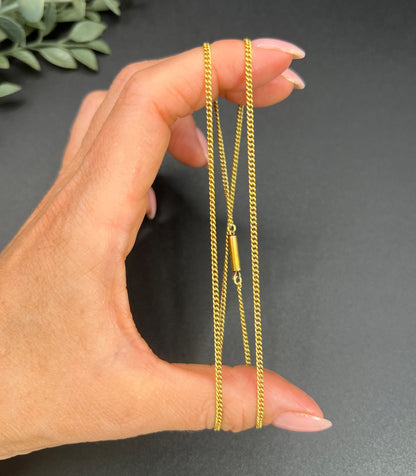 A yellow gold chain necklace, held in a hand