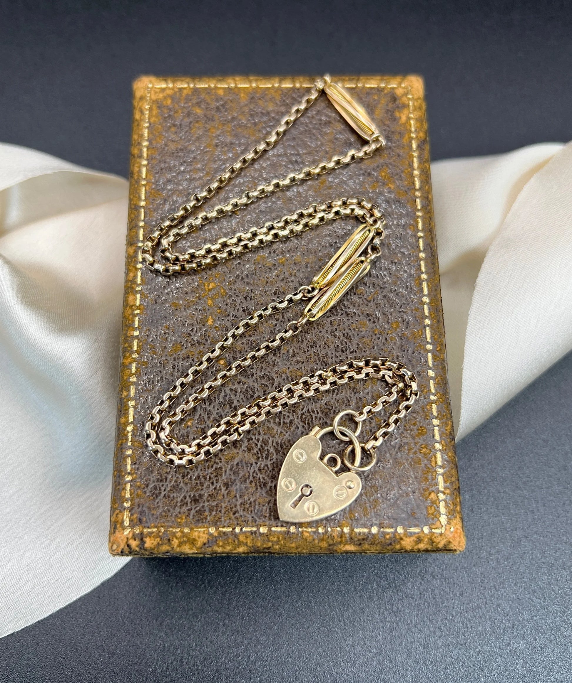 A yellow gold fancy link chain with a heart padlock