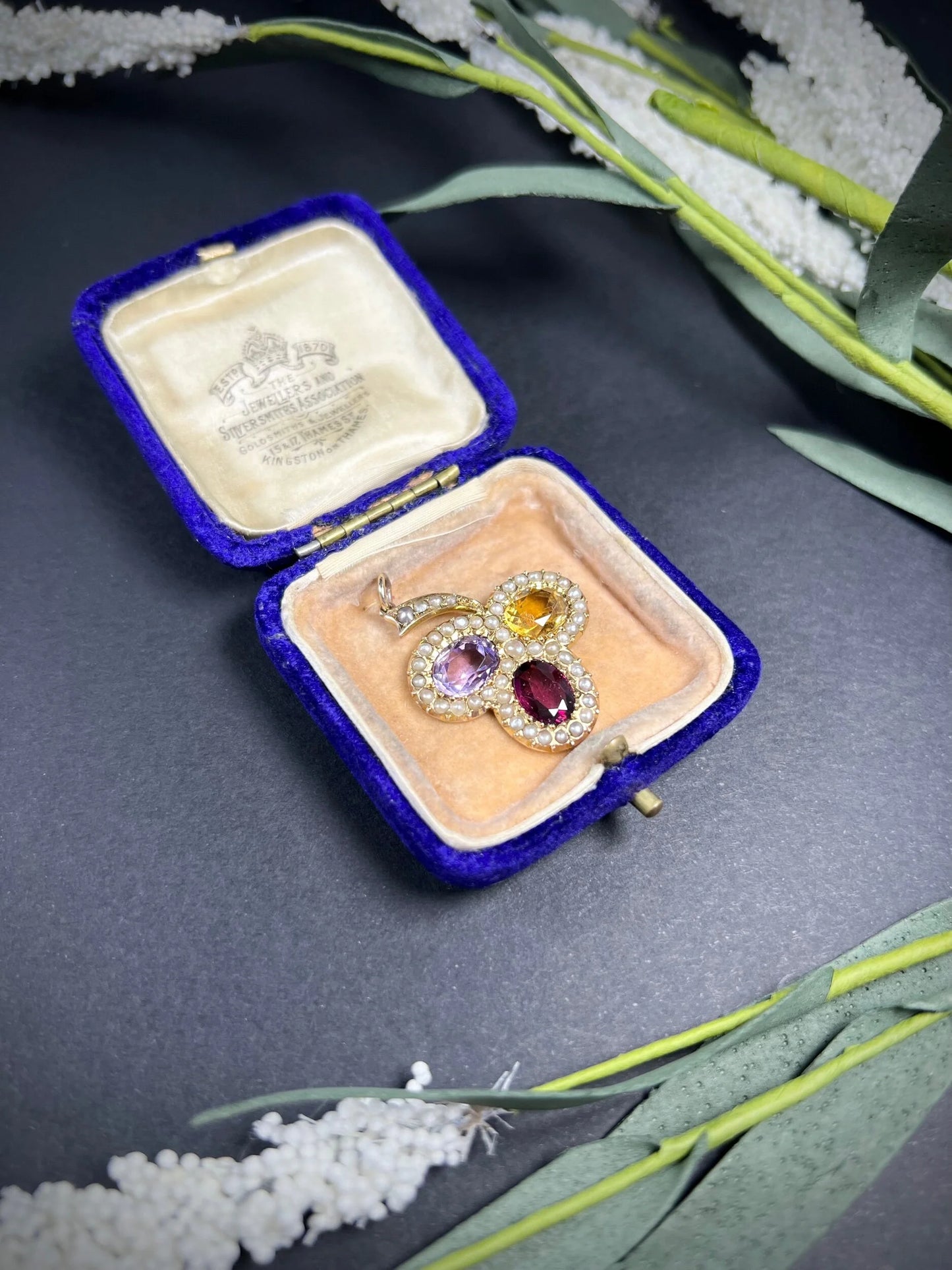 A yellow gold clover pendant with amethyst, citrine, garnet and seed pearls, in an antique box