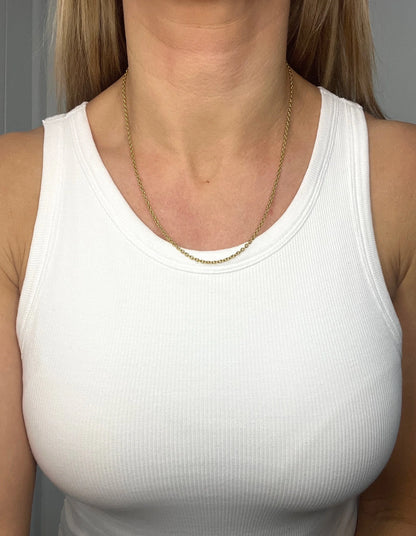 A yellow gold trace link chain necklace, modelled by a woman wearing a white top