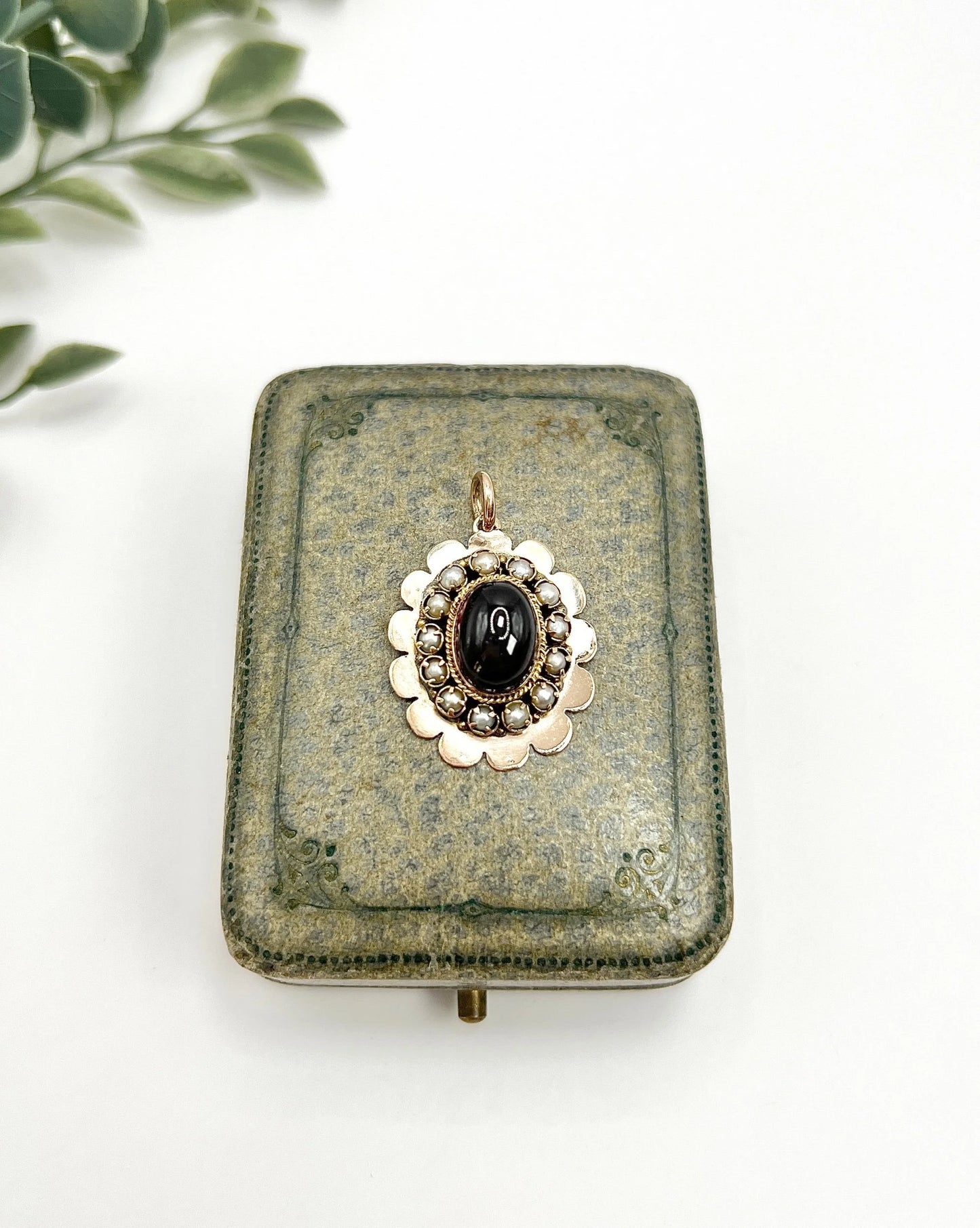 A cabochon garnet pendant with a seed pearl border in rose gold