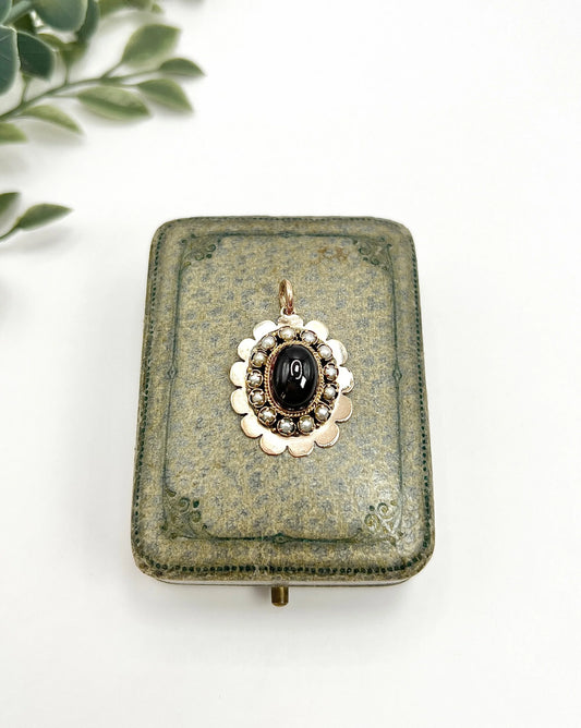 A cabochon garnet pendant with a seed pearl border in rose gold