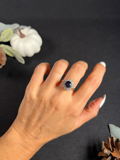 A round sapphire and diamond cluster ring, modelled on a hand