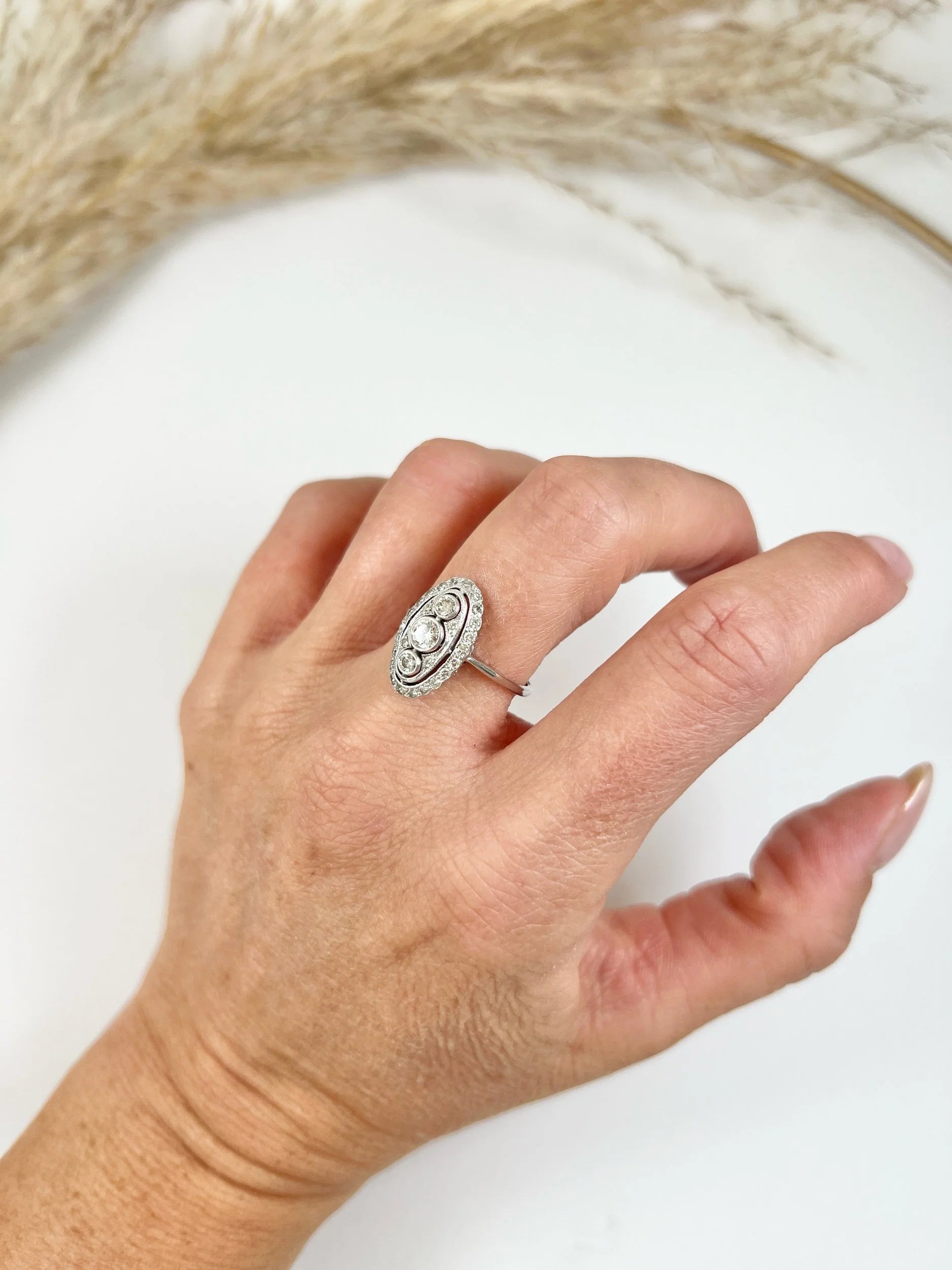 Antique 18 Carat White Gold Three Stone Diamond Oval Halo Ring, Circa 1910