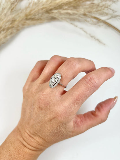 Antique 18 Carat White Gold Three Stone Diamond Oval Halo Ring, Circa 1910
