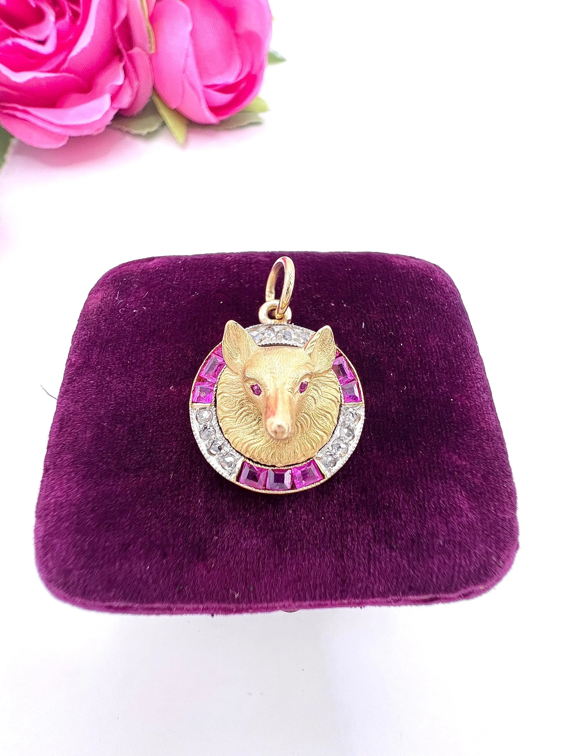 A fox head pendant in yellow gold with a ruby and diamond border