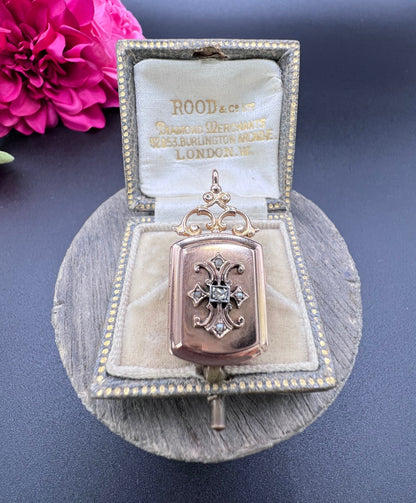 A yellow gold ornate locket with diamond fleur-de-lis detail, in an antique box
