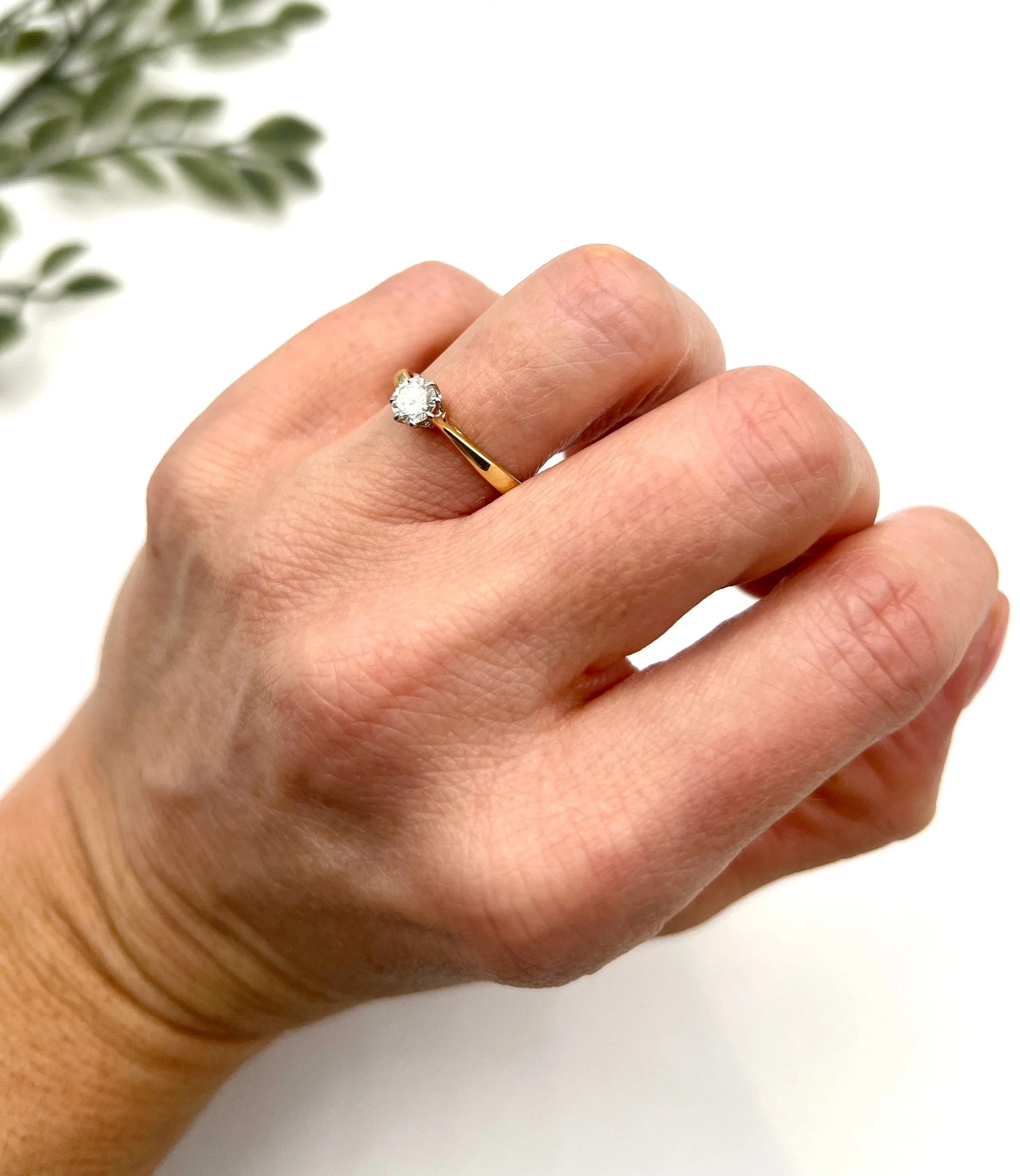 A single stone brilliant cut diamond ring claw set in platinum and yellow gold, modelled on a hand