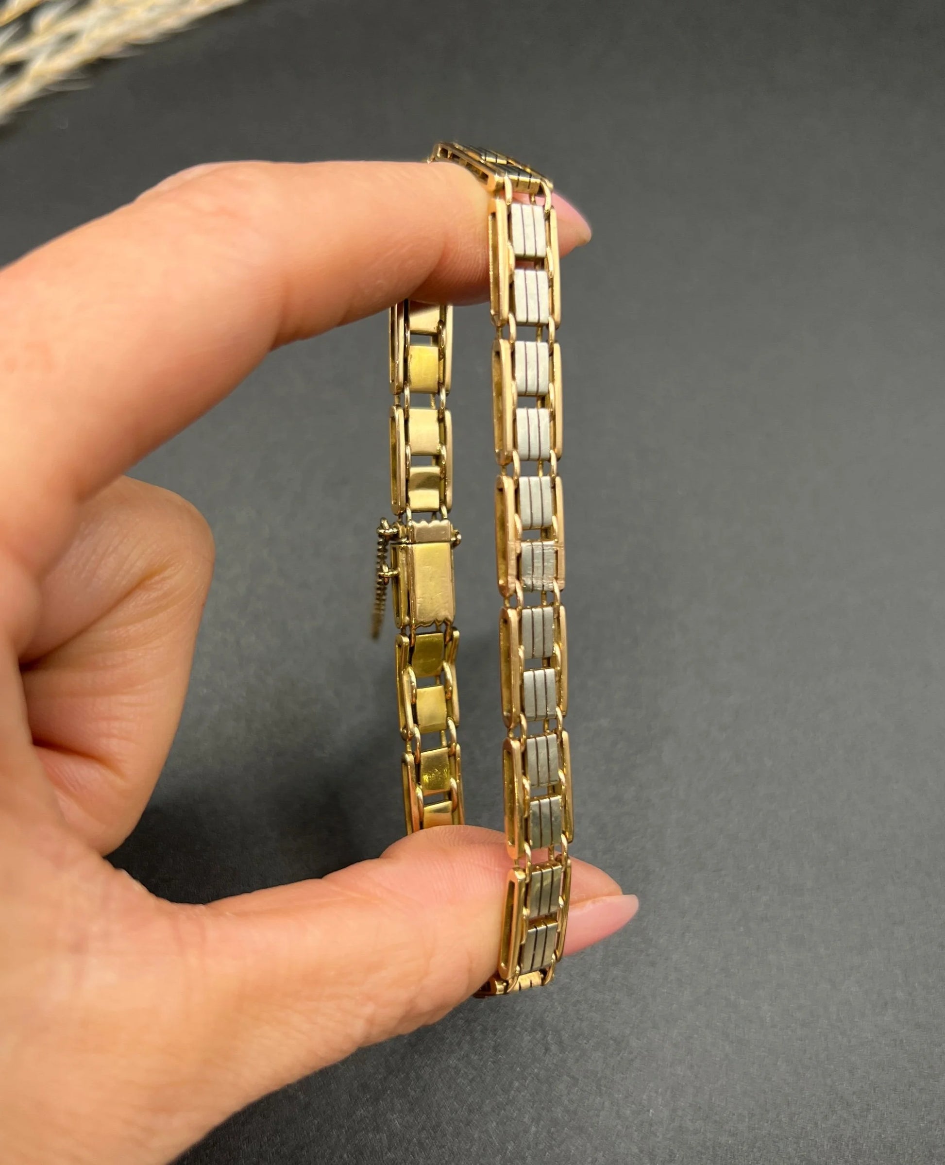 A gold and platinum gate bracelet, held in a hand
