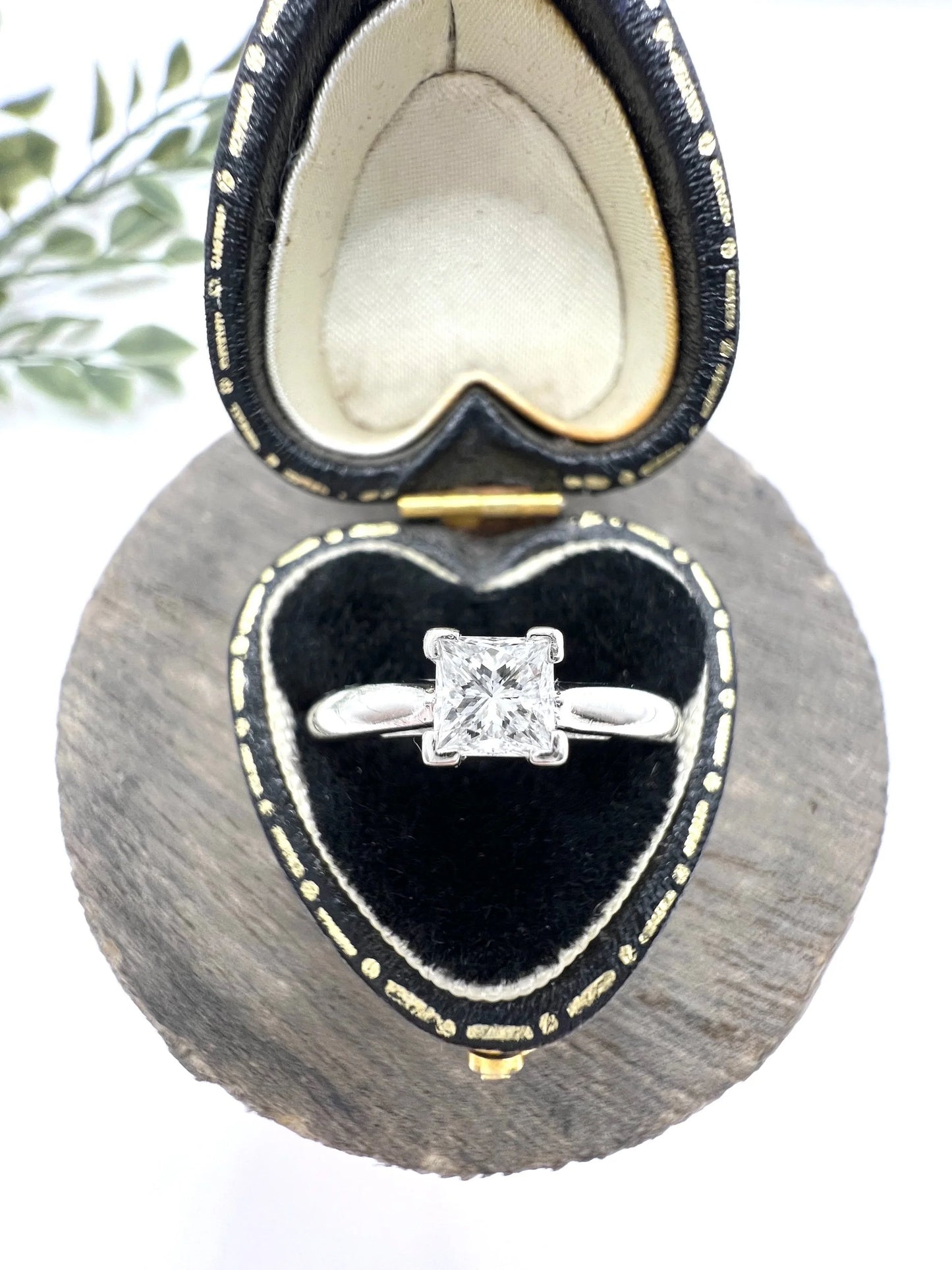 A princess cut diamond solitaire ring in platinum, in a heart-shaped ring box