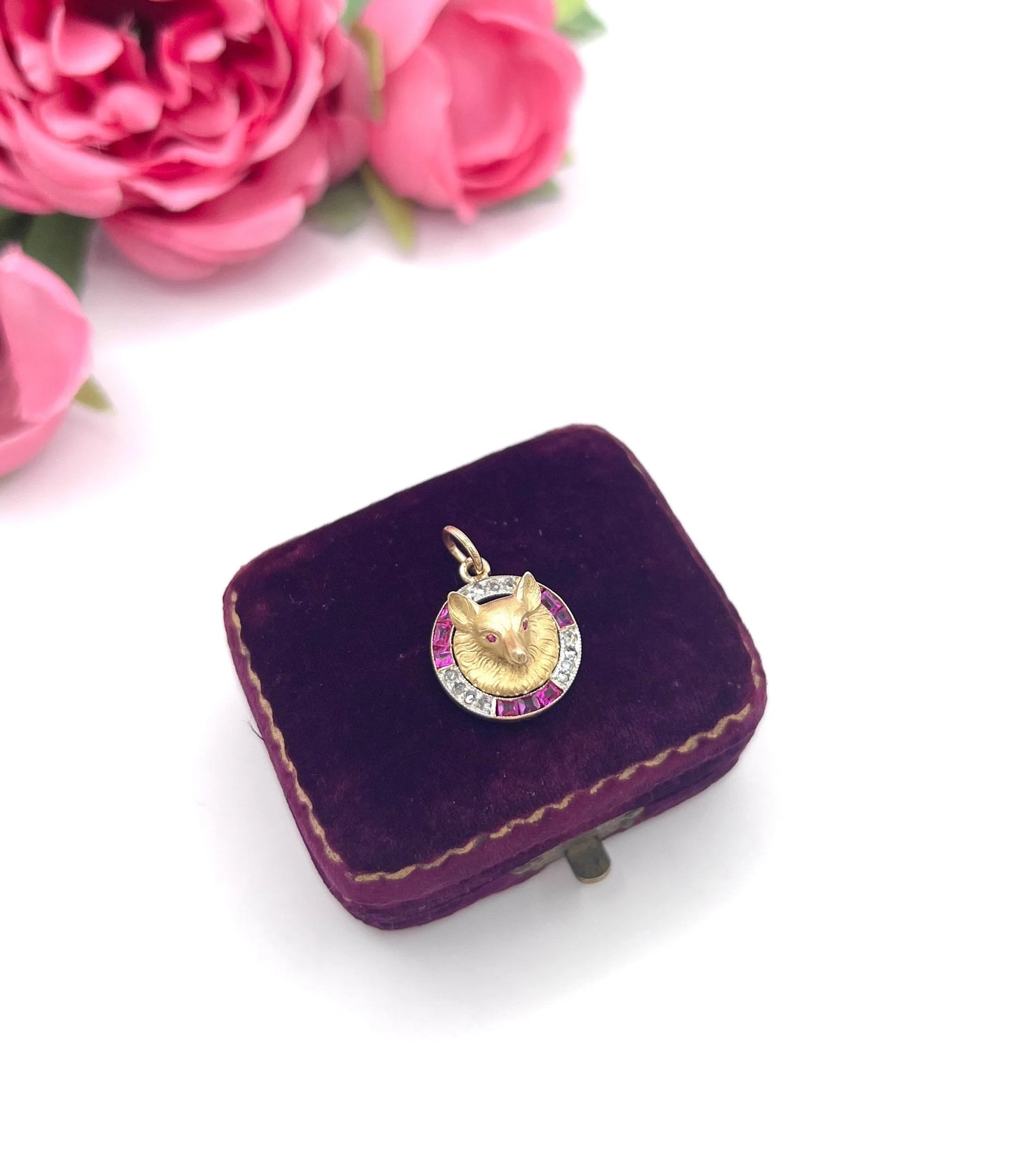 A fox head pendant in yellow gold with a ruby and diamond border