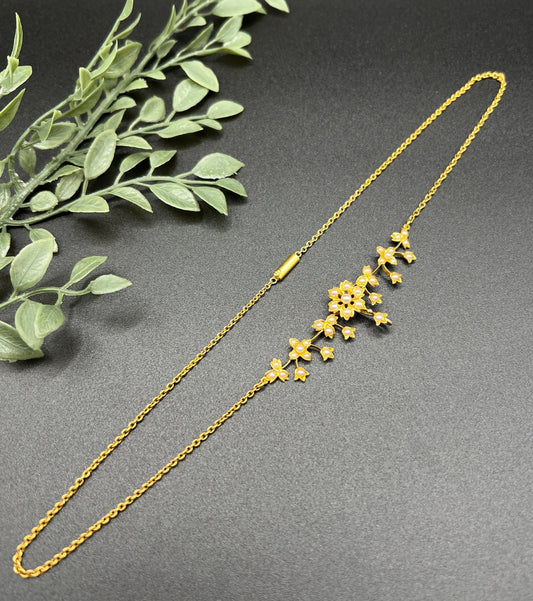A yellow gold floral pendant necklace with seed pearls