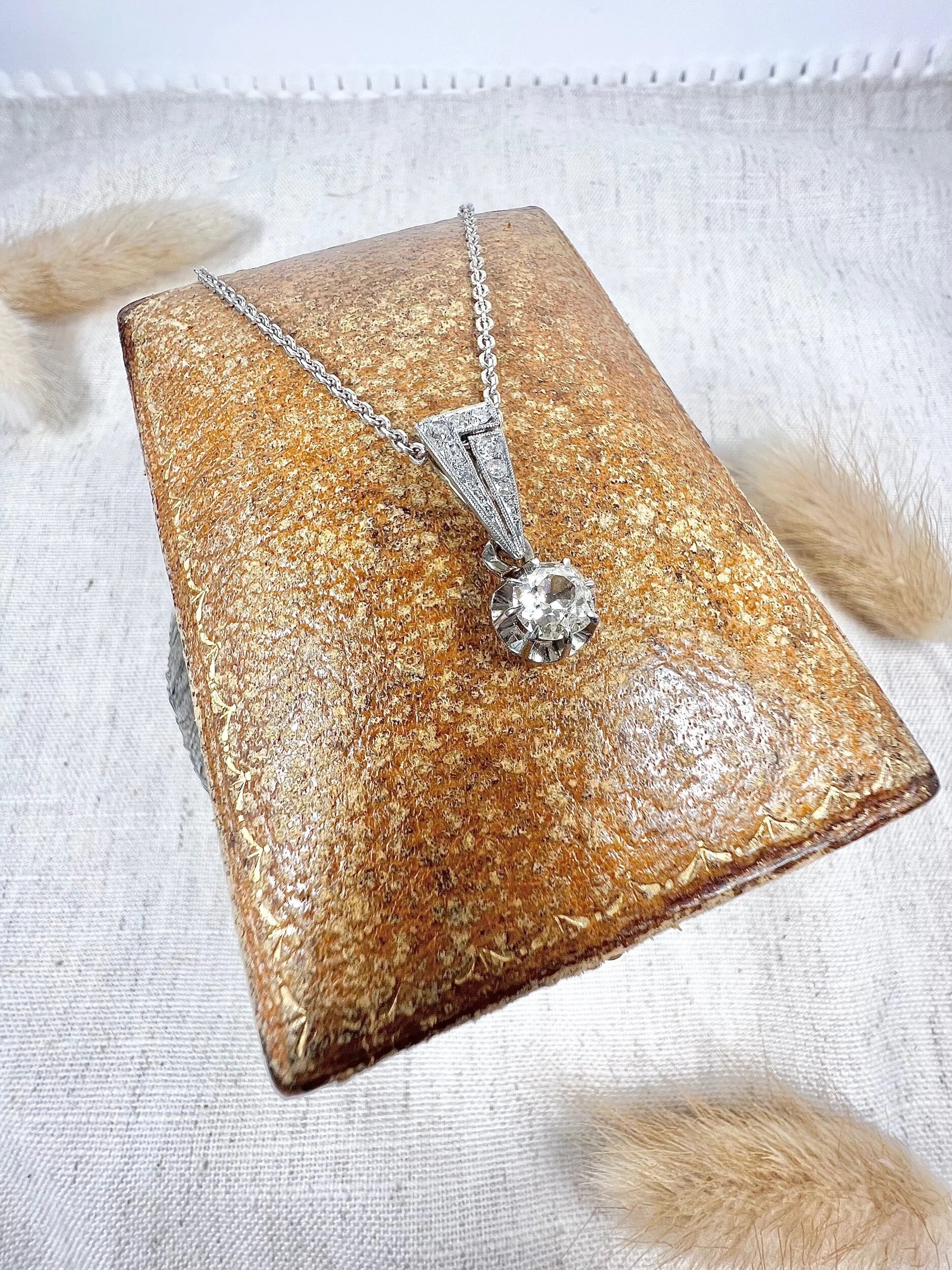 An old cut diamond pendant in white metal with a matching chain, on an antique box