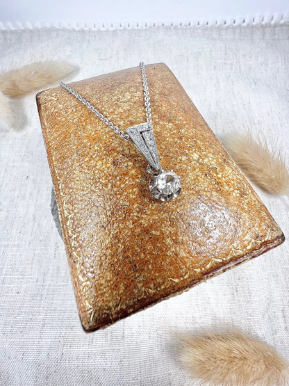 An old cut diamond pendant in white metal with a matching chain, on an antique box