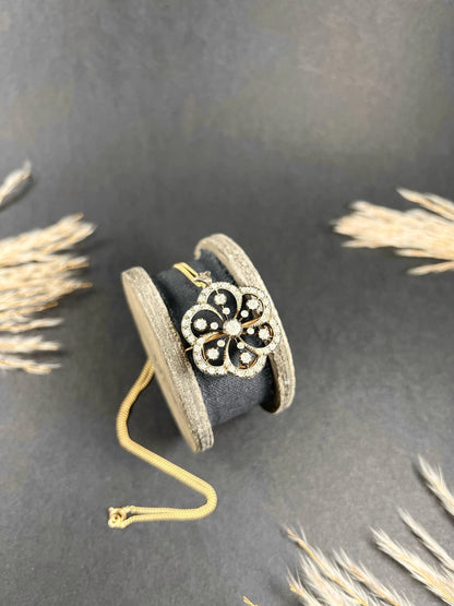 A floral design diamond set pendant/brooch, with a gold chain, on an antique box