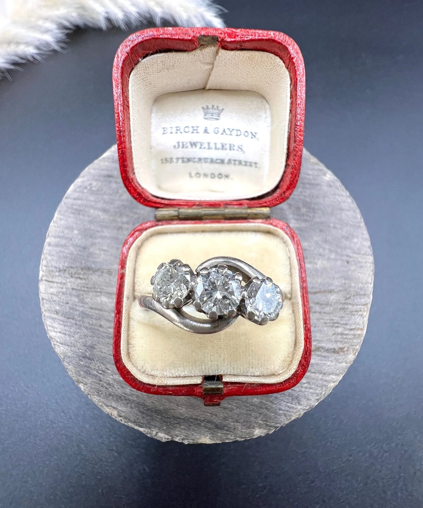 A three stone diamond crossover ring, in a red antique ring box