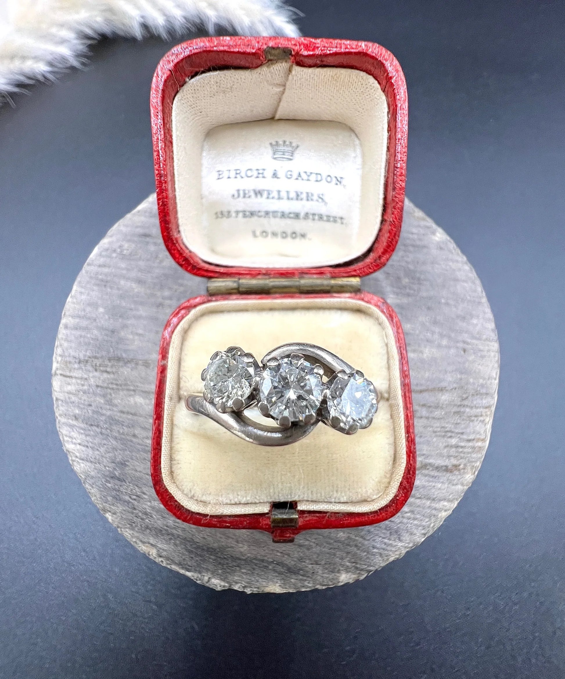 A three stone diamond crossover ring, in a red antique ring box