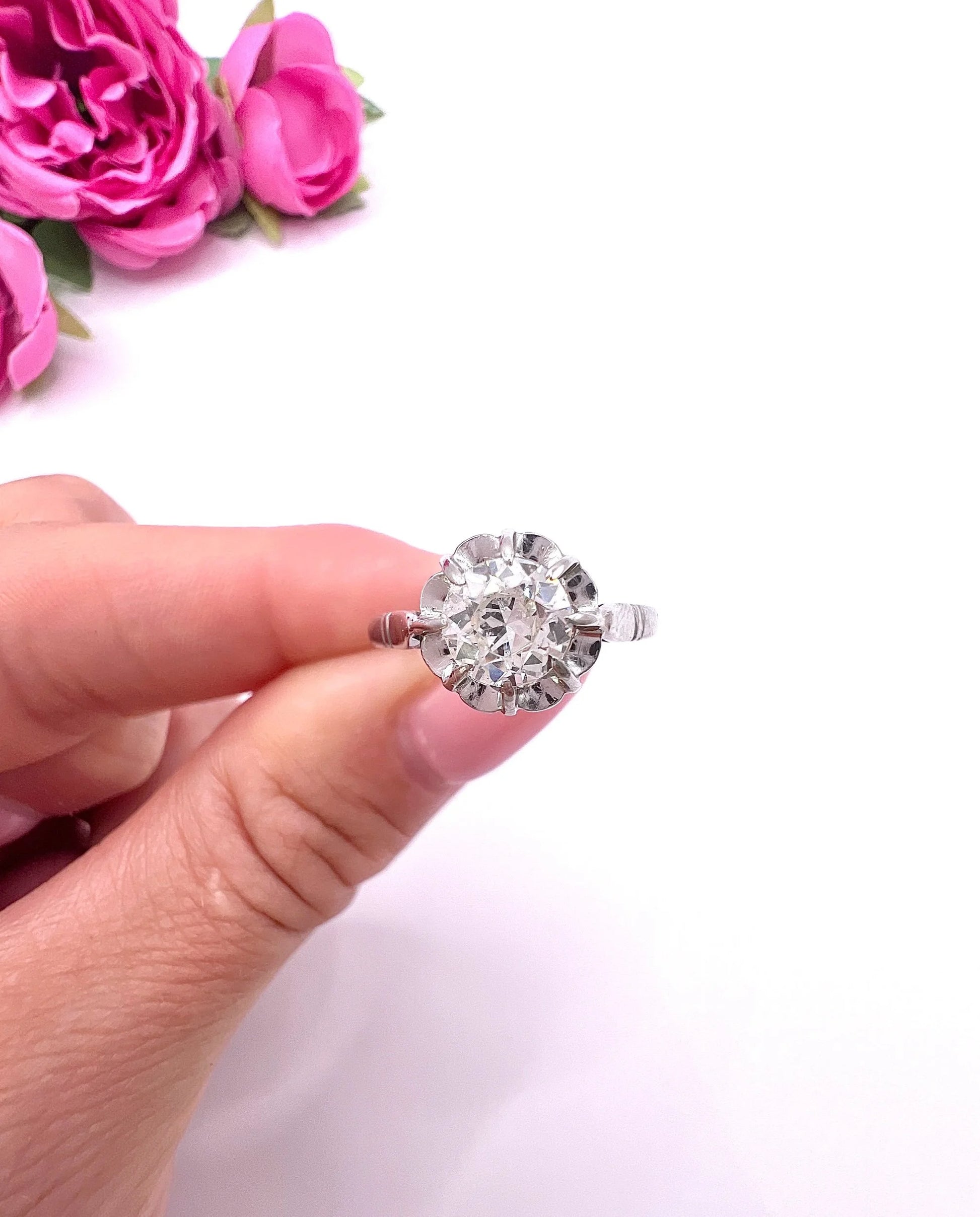 A solitaire diamond ring in platinum, held in a hand