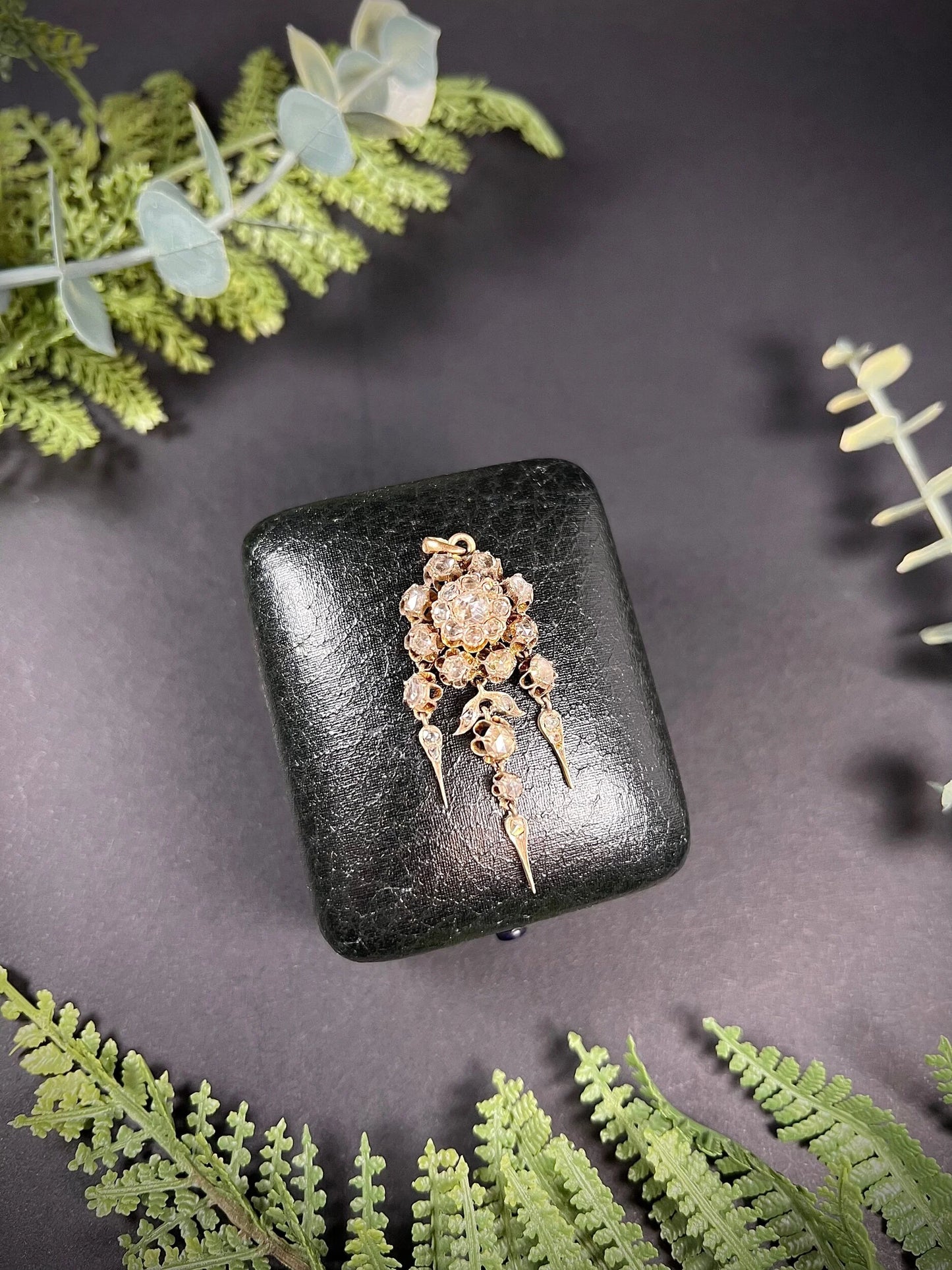 A yellow gold pendant with old cut diamonds, on a black antique box
