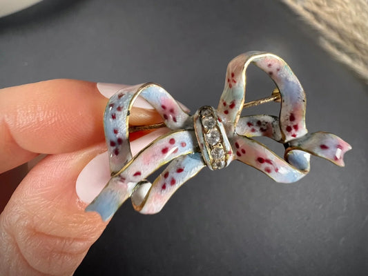 A blue and pink enamel bow brooch with diamonds in yellow gold