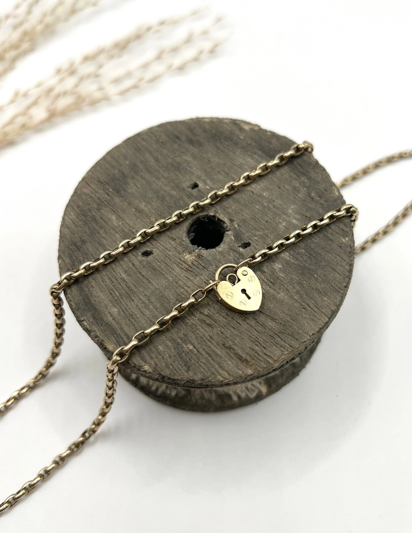 A gold belcher link chain with a heart shaped padlock clasp pendant