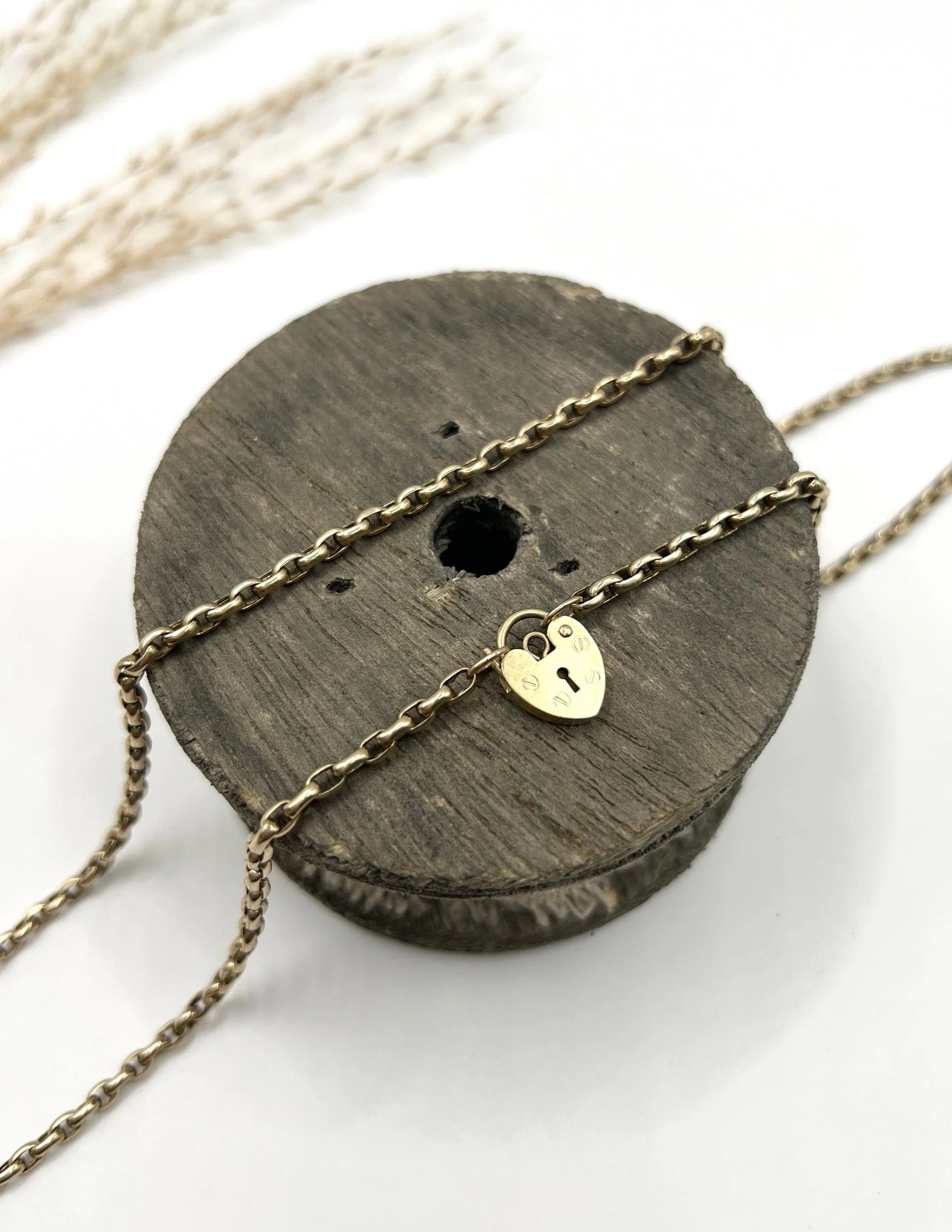 A gold belcher link chain with a heart shaped padlock clasp pendant
