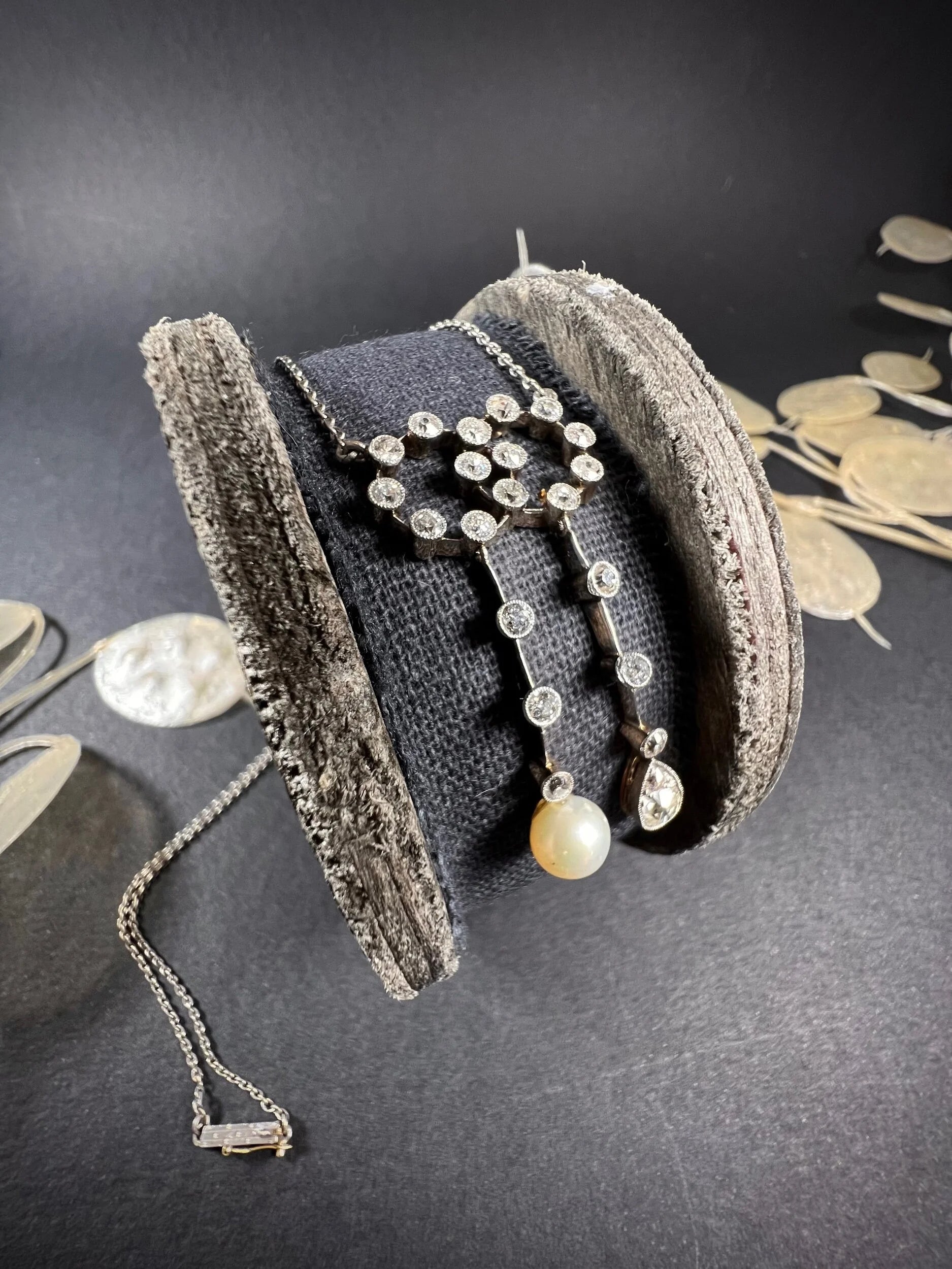 An antique diamond and pearl double drop pendant necklace, on a wooden spool