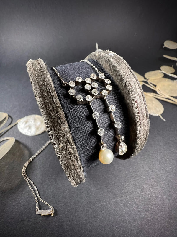 An antique diamond and pearl double drop pendant necklace, on a wooden spool