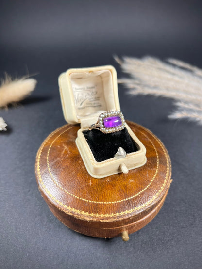 A cabochon amethyst and pearl halo cluster ring in gold, in a ring box