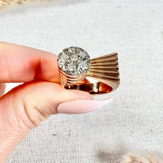 A rose gold diamond set cocktail ring, held in a hand