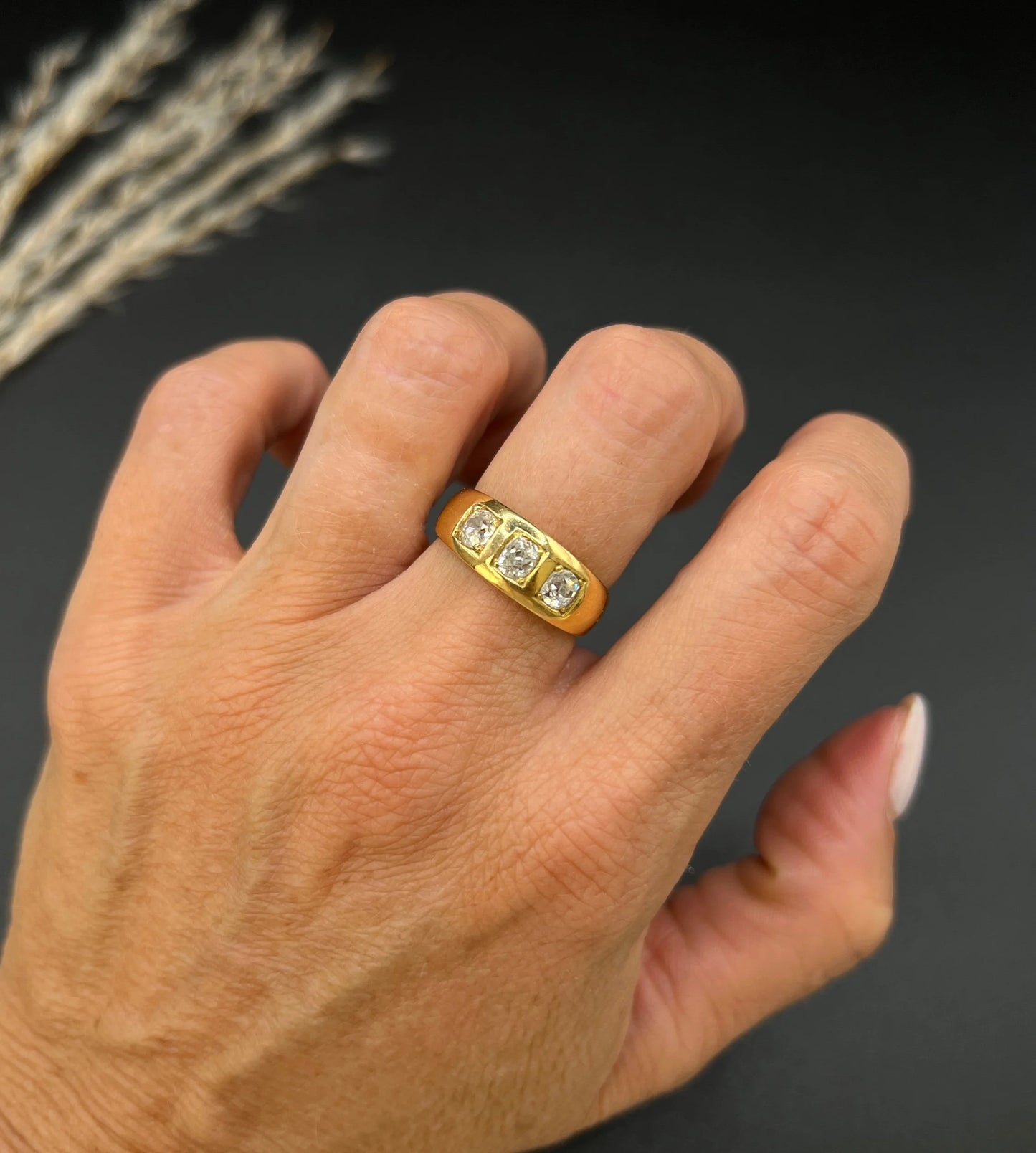 A three stone old cut diamond ring in yellow gold, modelled on a hand
