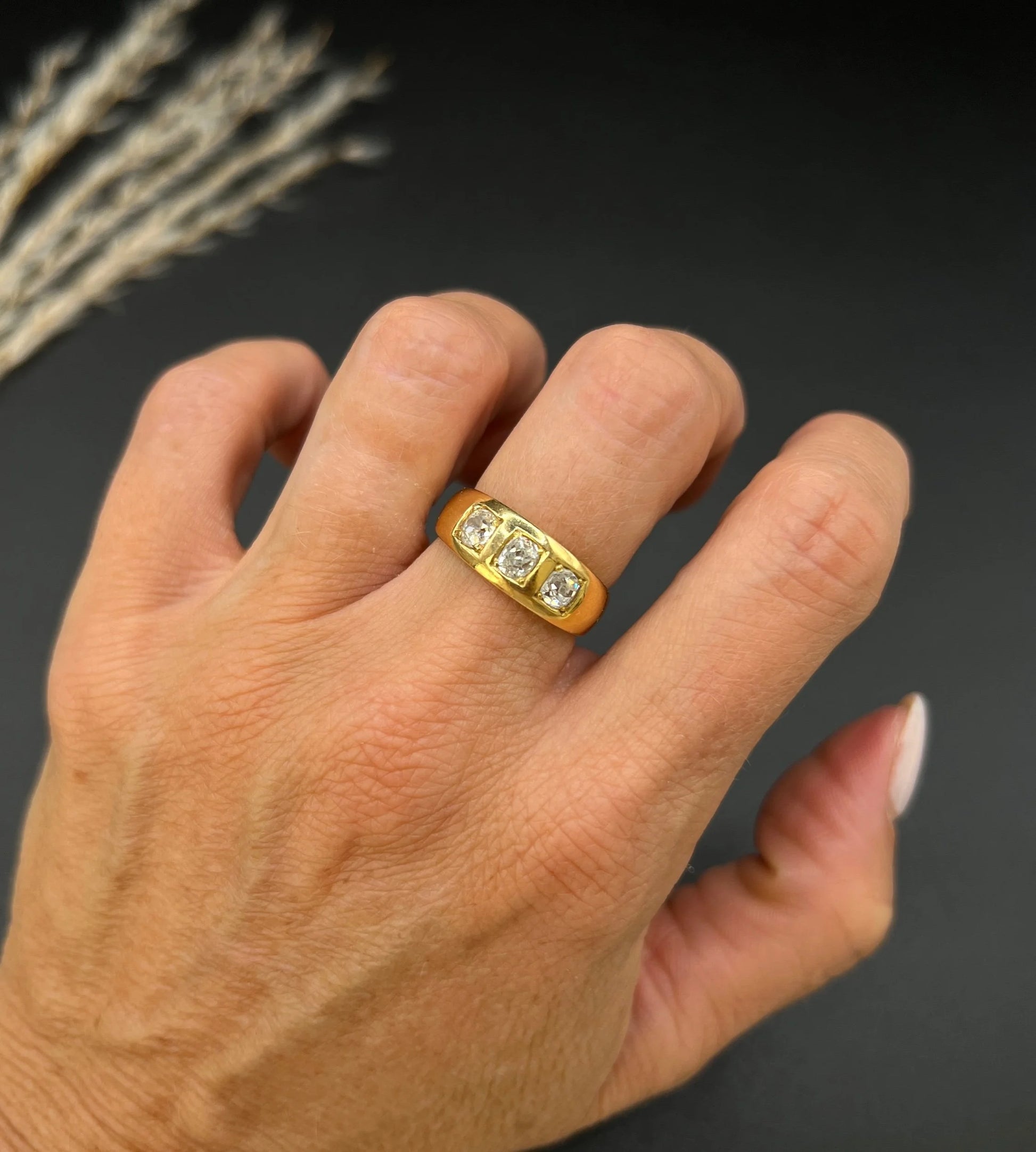 A three stone old cut diamond ring in yellow gold, modelled on a hand