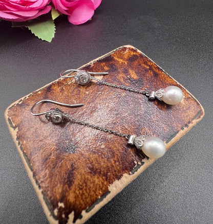 A pair of long drop platinum earrings with pearls and diamonds