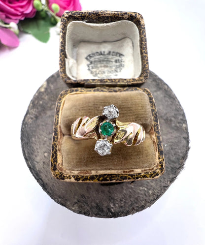 A three stone emerald and diamond ring in yellow and white gold, in an antique ring box