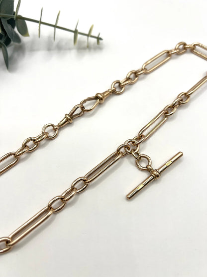 A rose gold trombone and fetter link Albert chain, on a white background