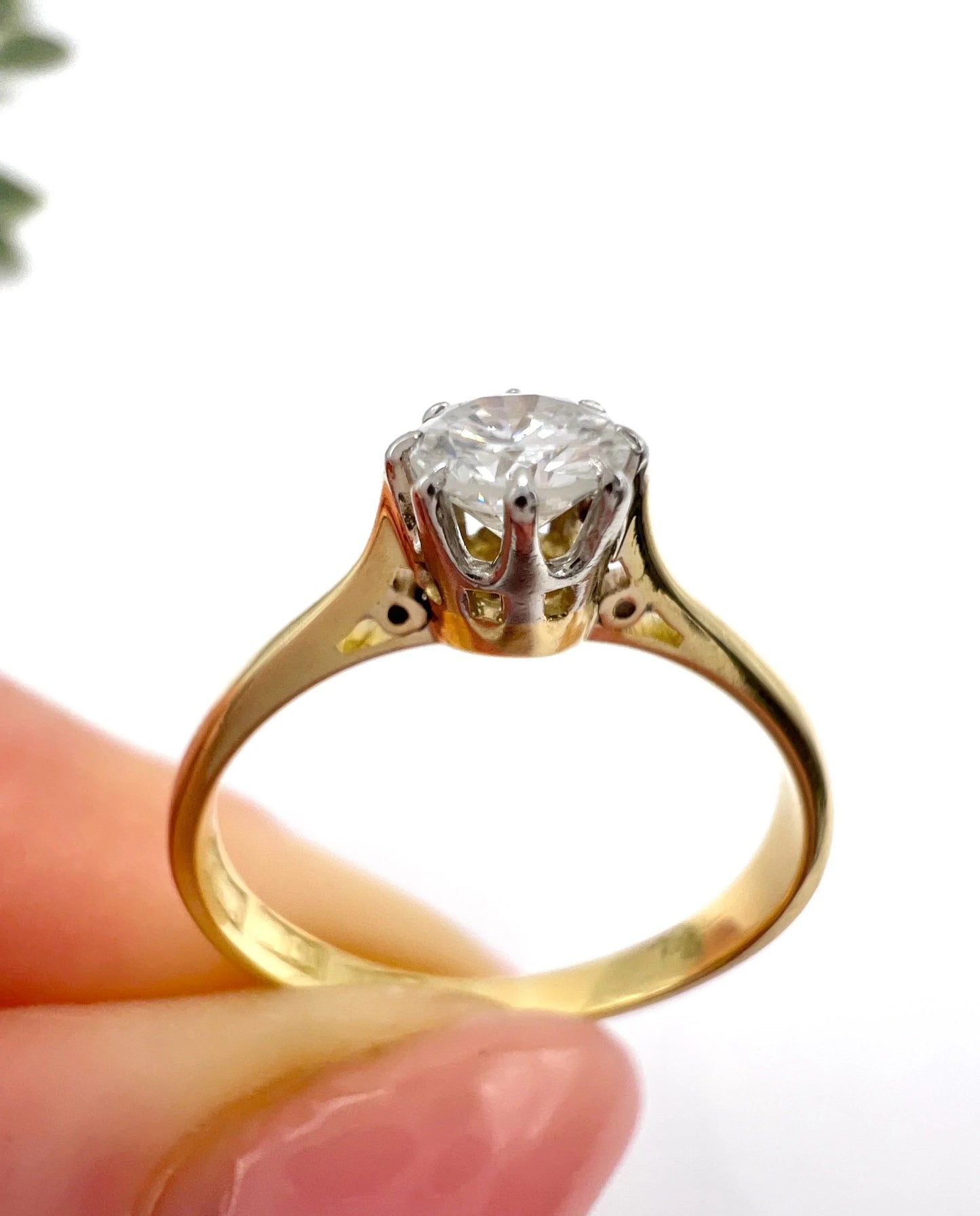 A single stone brilliant cut diamond ring claw set in platinum and yellow gold, held in a hand