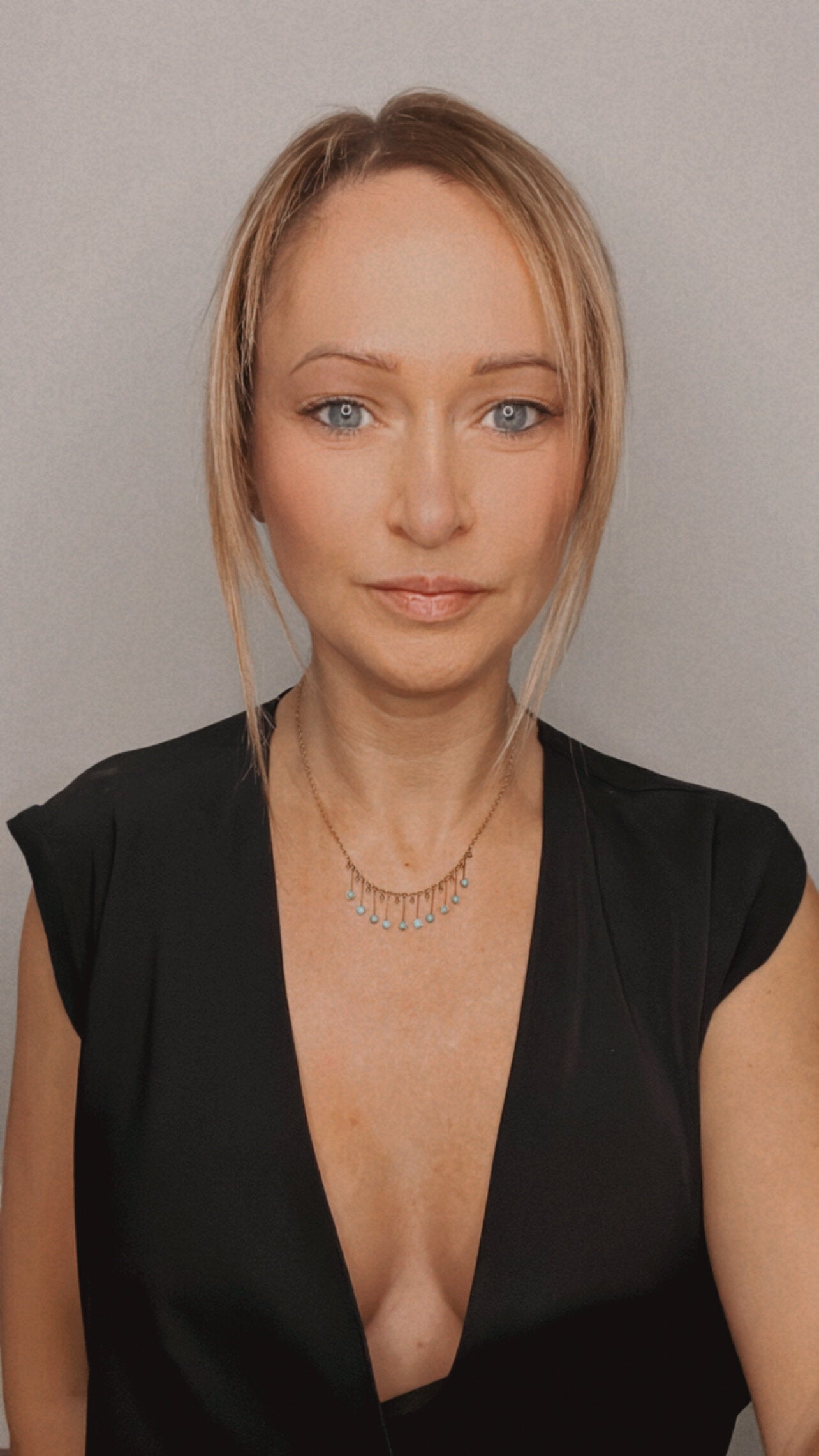 A gold negligee pendant necklace with turquoise drops, modelled by a woman