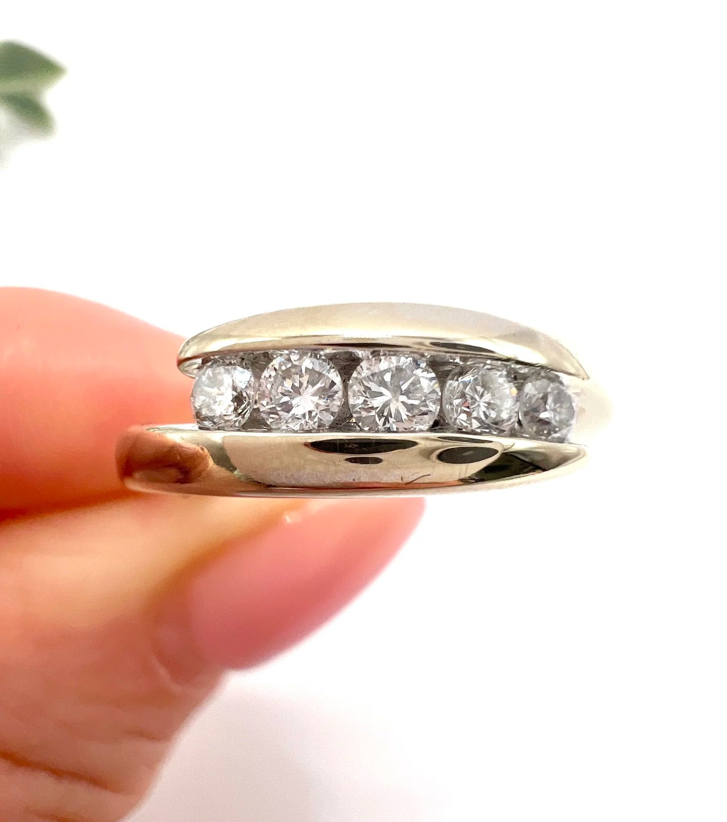 A five stone brilliant cut diamond ring in white gold, held in a hand