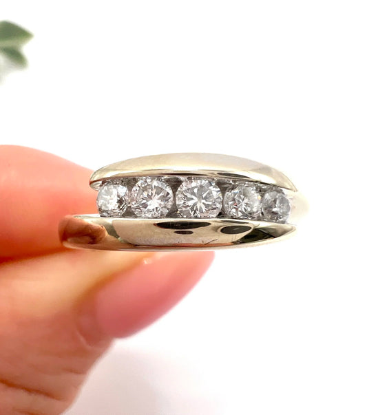 A five stone brilliant cut diamond ring in white gold, held in a hand
