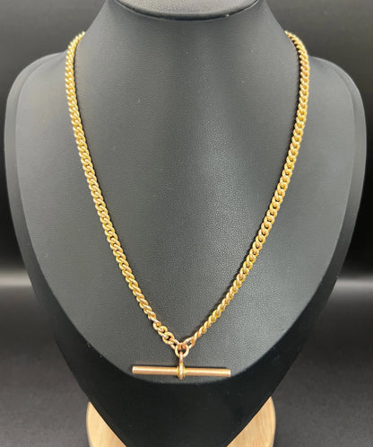 A yellow gold curb link Albert watch chain, on a black jewellery bust
